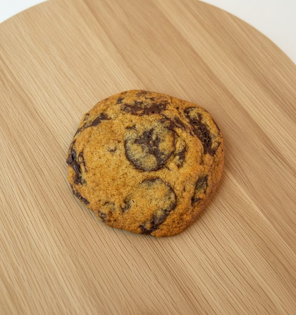 Chocolate chunk cookie with pooled chocolate on light wood