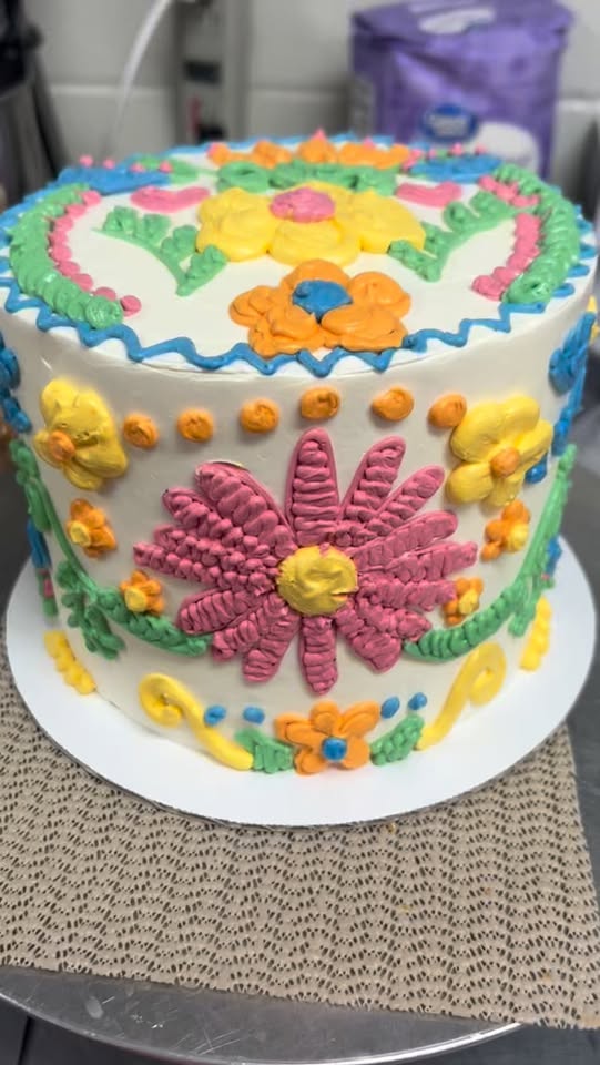 A cake covered in buttercream flowers, piped by hand