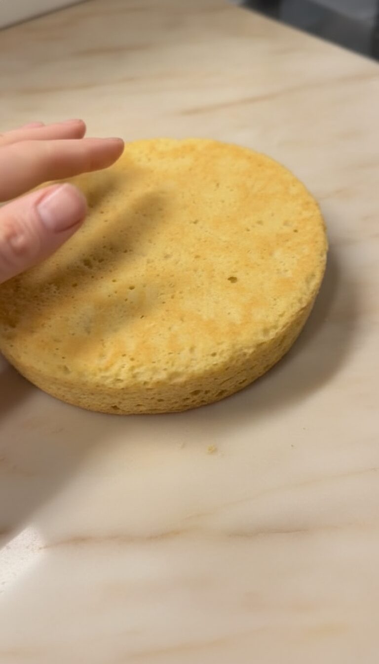 A hand setting a cake layer onto the stack